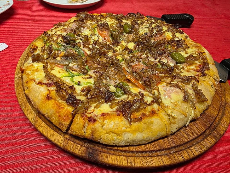 Whole thick onion and cheese pizza on a wooden serving board.