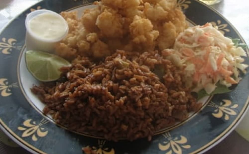Dunkler Reis mit Straucherbsen, frittiertem Seafood, Krautsalat, Soße und Limette.