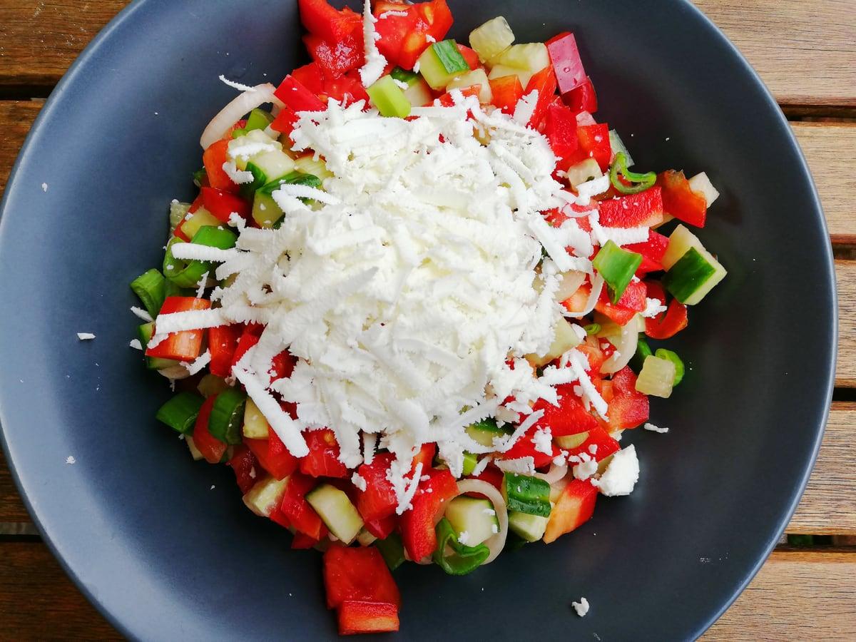 Tigela de tomate picado, pepino, pimentão, cebola e queijo branco ralado em salmoura.