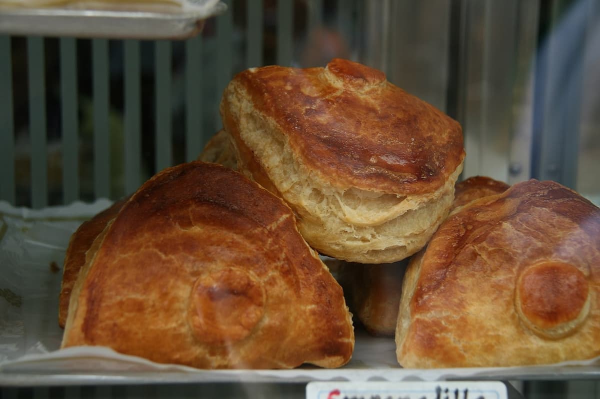 Golden folded tuna pastries displayed in a bakery case.