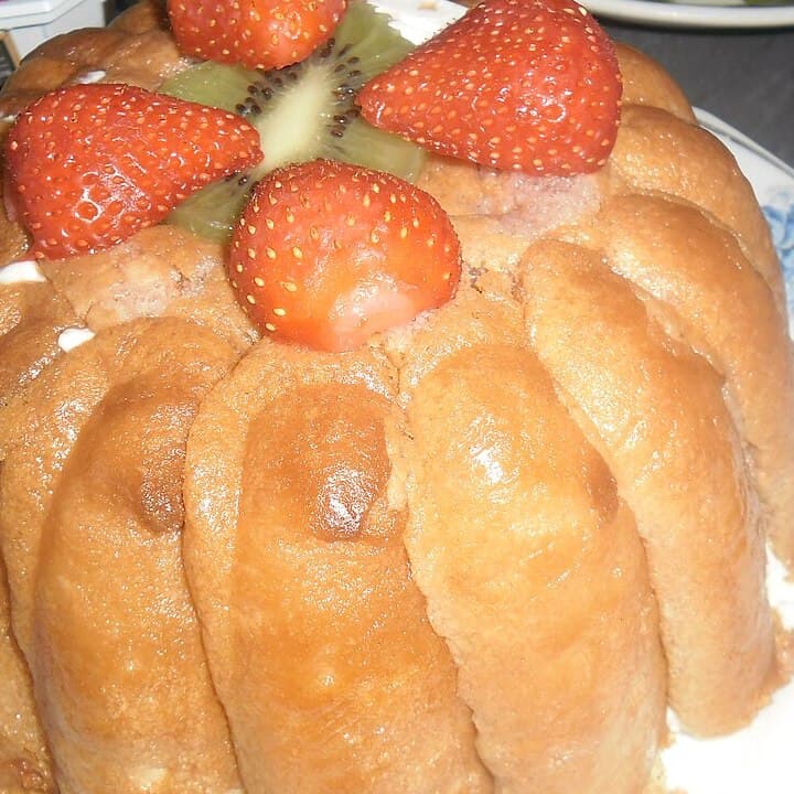 Ein geformtes Erdbeerdessert mit Löffelbiskuitseiten und Erdbeeren oben.