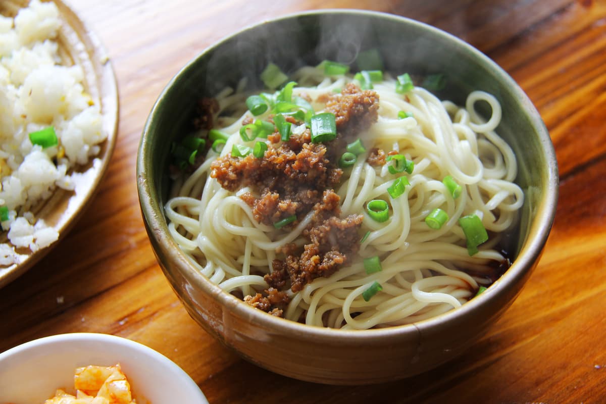 Würzige Nudeln mit Chiliöl, Hackfleisch und Frühlingszwiebeln in einer Schüssel.