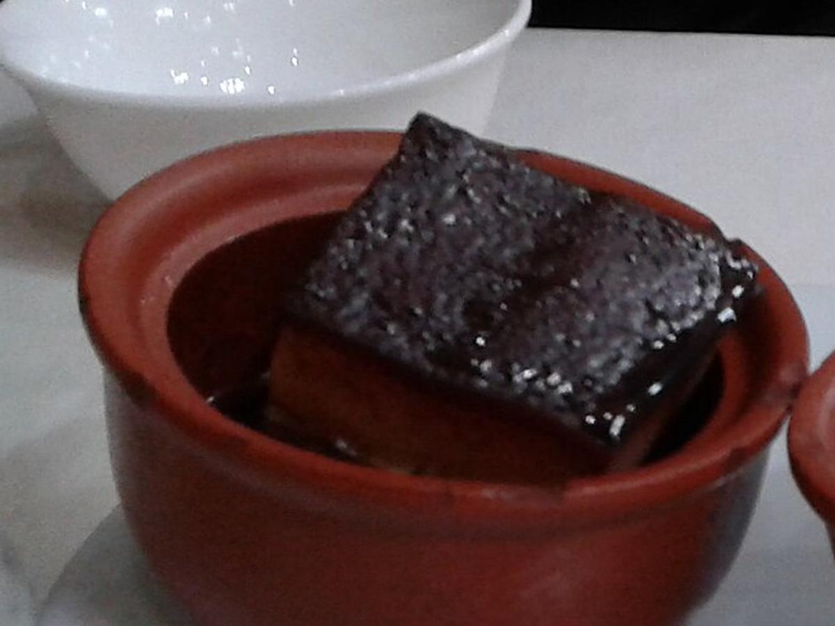 Cube brillant de ventre de porc braisé dans un petit bol en terre cuite.
