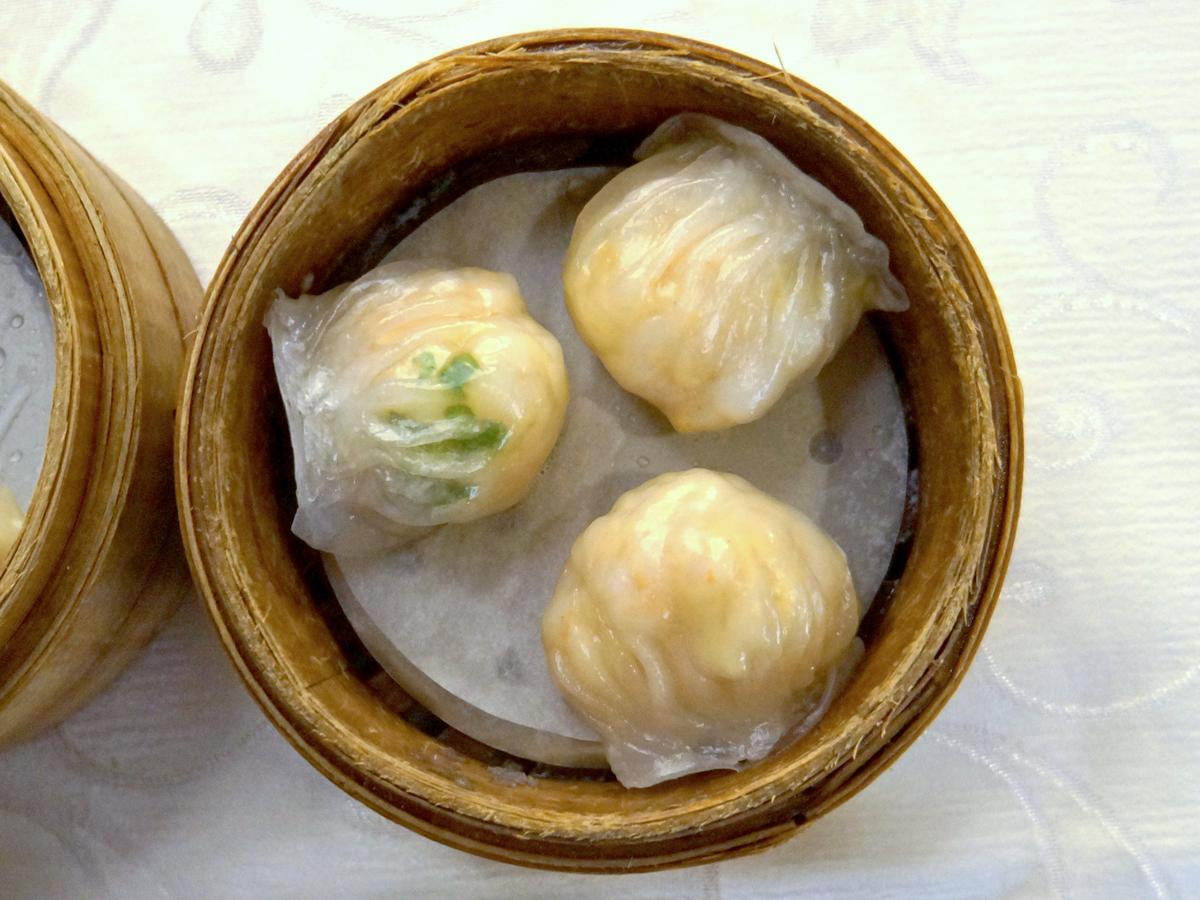 Tiga dumpling udang transparan dalam kukusan bambu.