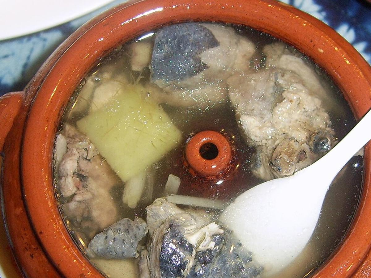 Tontopf mit klarem Hühnersuppen-Dampf und Hühnerstücken.