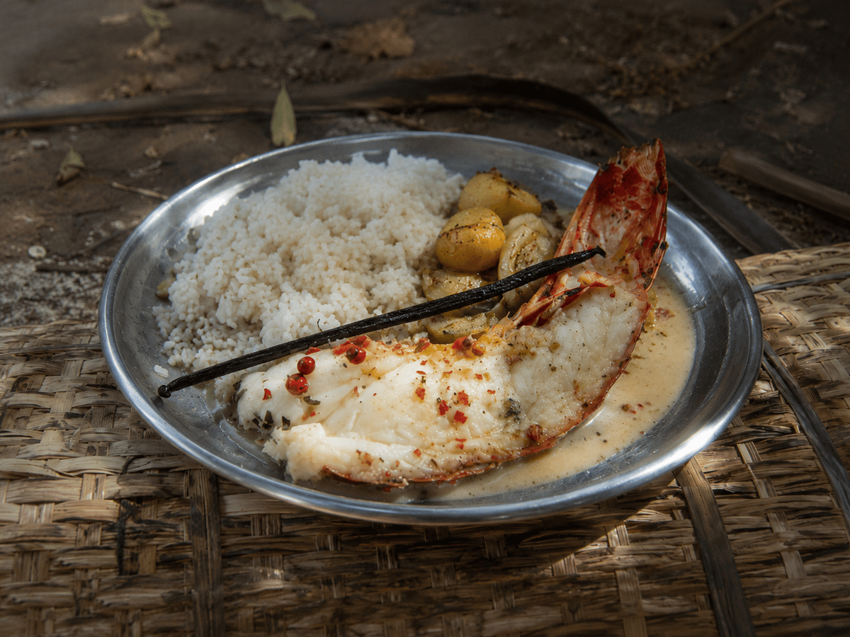 Split lobster tail in pale vanilla sauce with white rice and roasted vegetables.