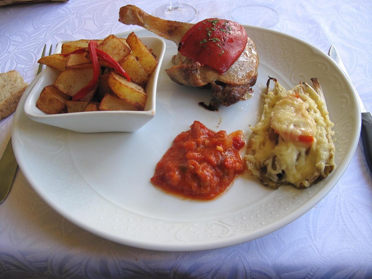 Teller mit knuspriger Entenkeule, Kartoffeln, Sauce und Beilage.