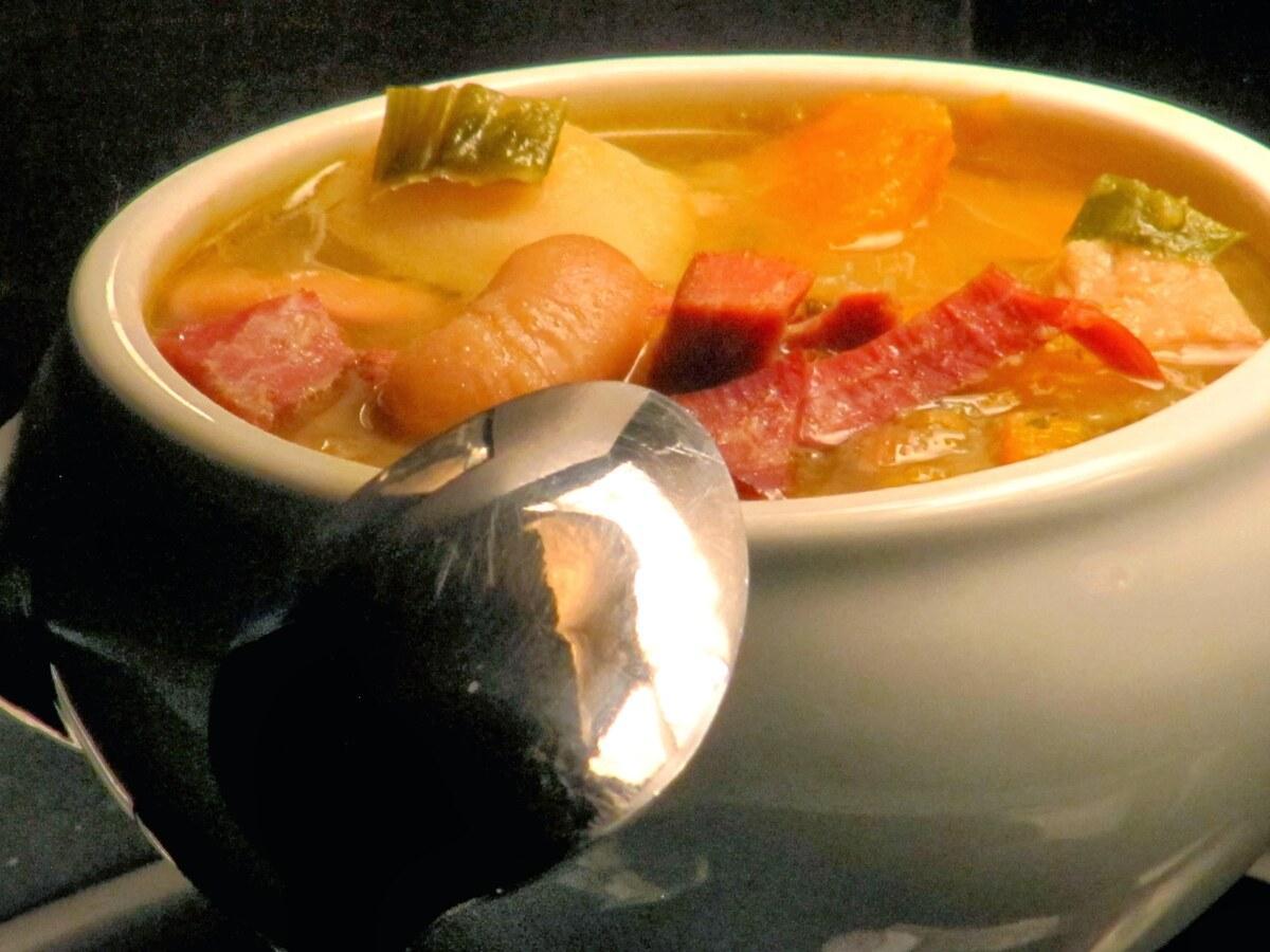 Tazón de sopa espesa de repollo, frijoles y verduras con una cuchara.