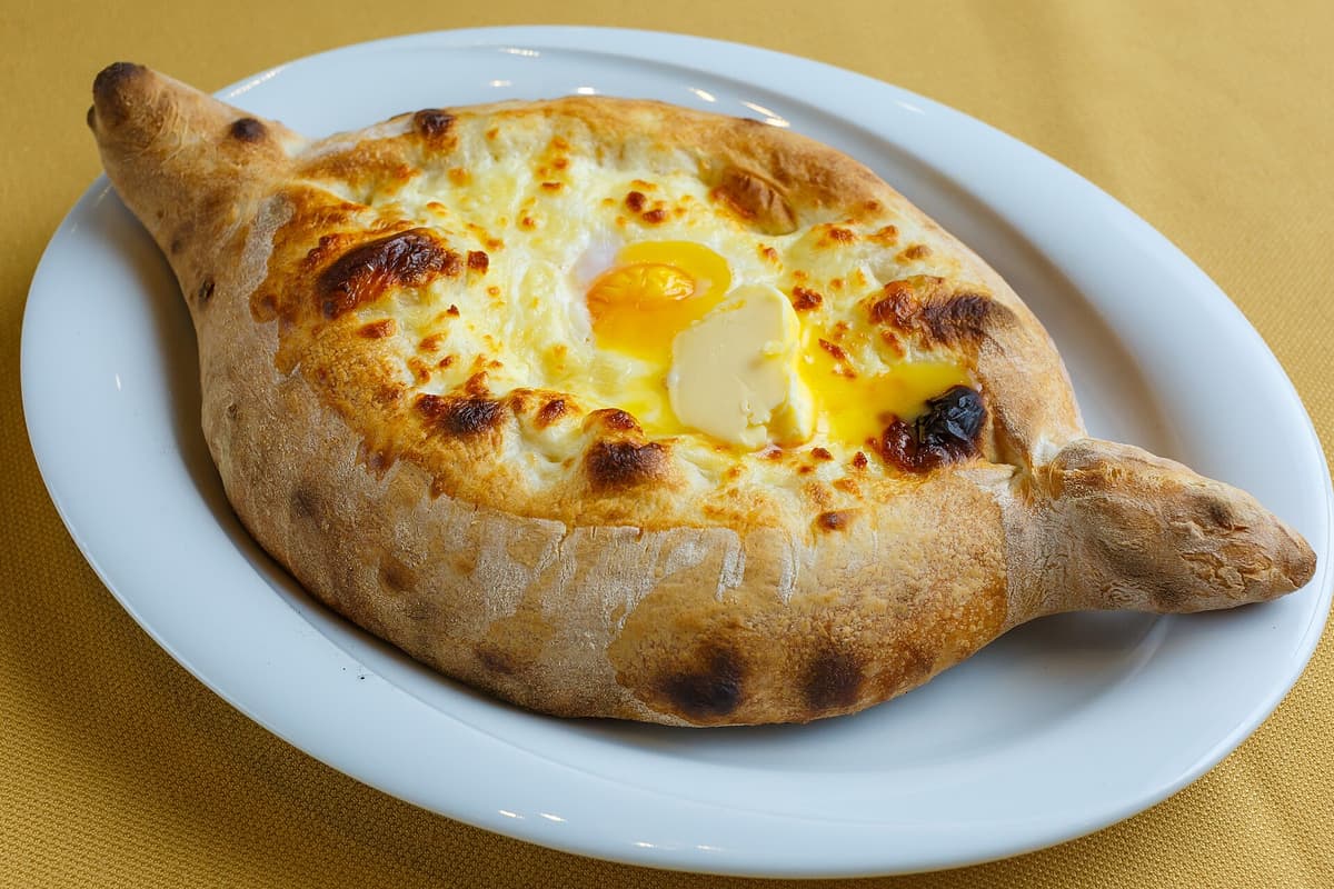 Boat-shaped cheese bread topped with a runny egg and butter.