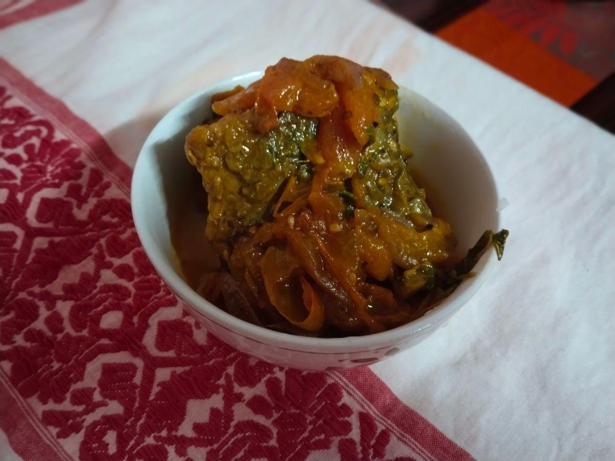 Bowl of sour fish curry with vegetables and a red-brown broth.