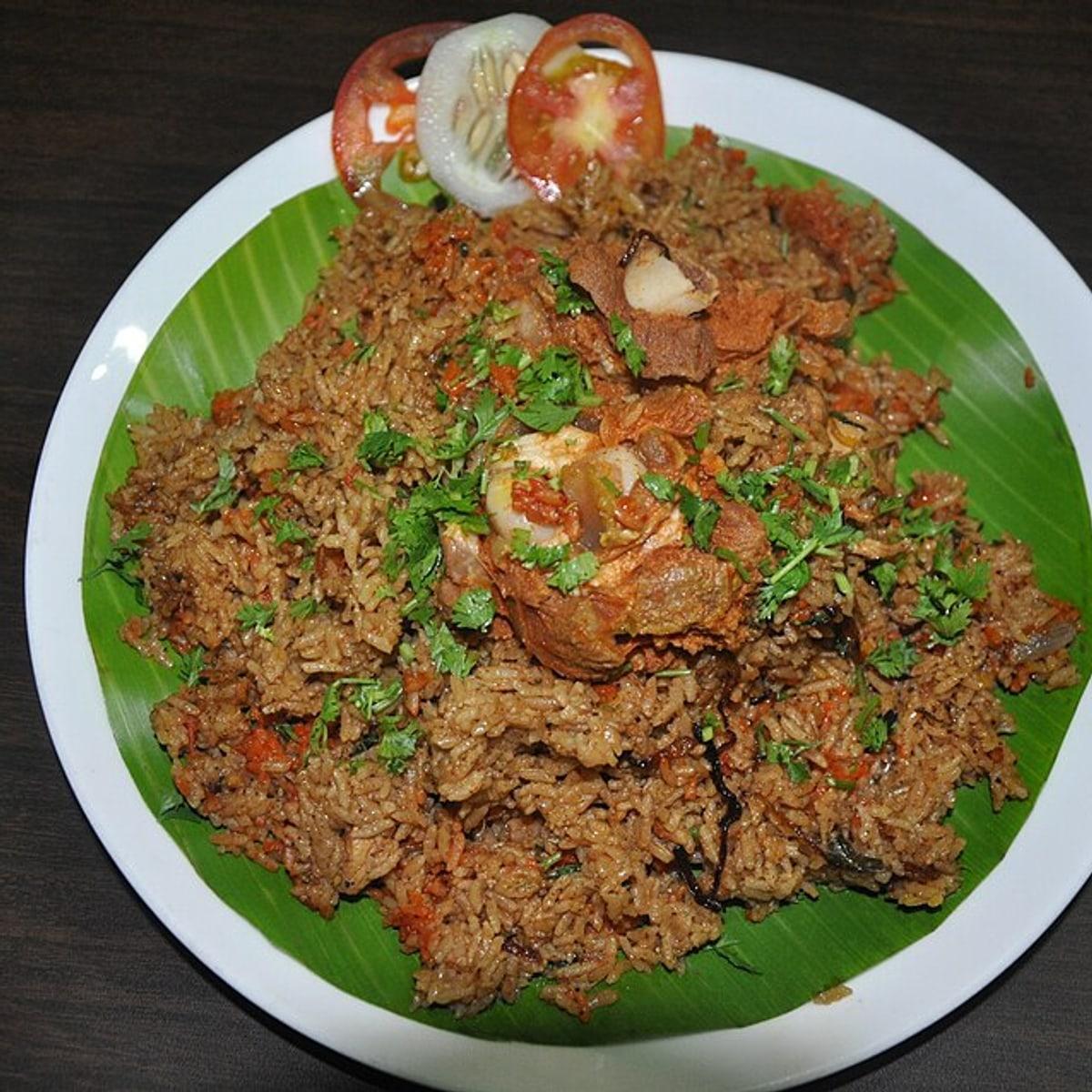 Plato de arroz especiado con piezas de carne, hierbas y cebolla en rodajas.