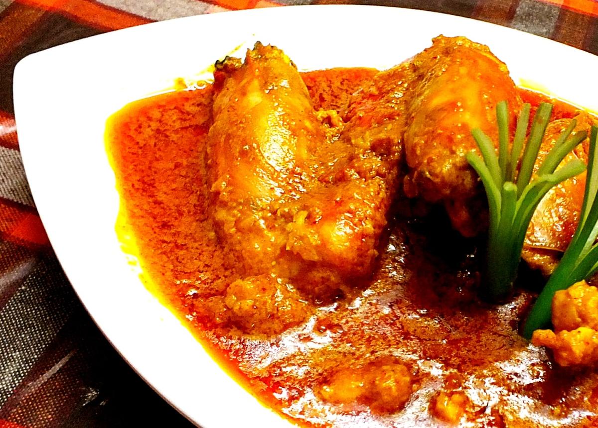 Camarones en salsa cremosa de coco rojo-dorada en un cuenco blanco.