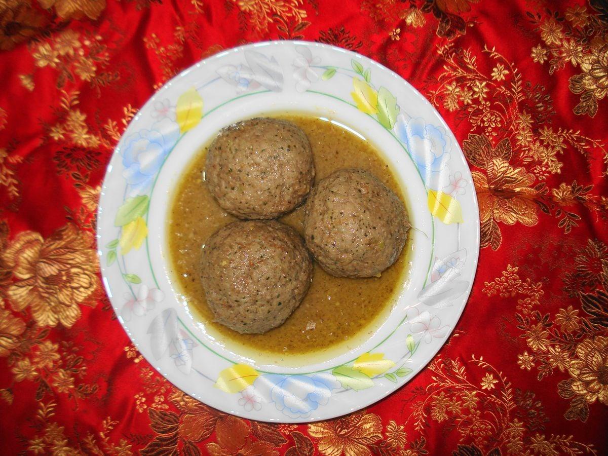 Teller mit großen Fleischbällchen in heller gelblicher Joghurtsauce.