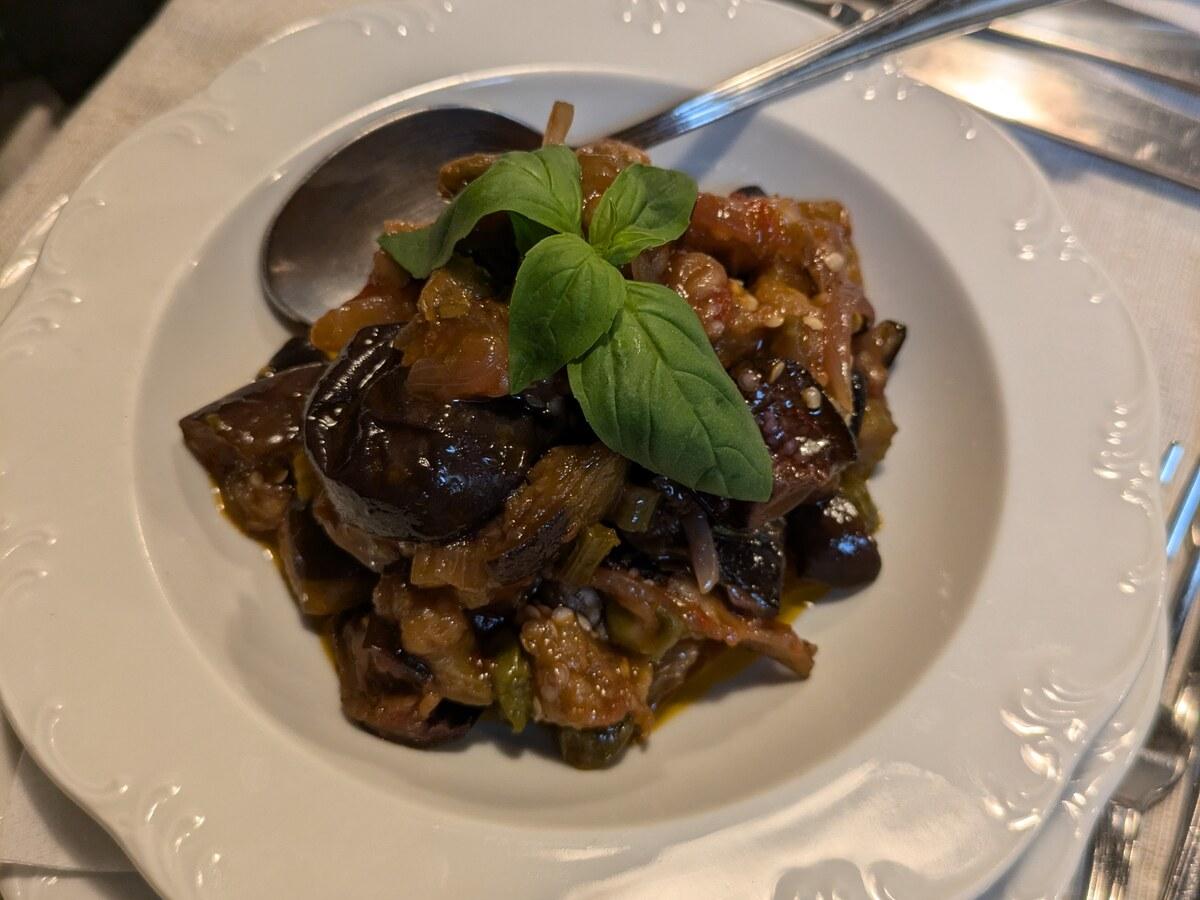 Süß-saures Auberginen-Relish mit Basilikum in weißer Schüssel.