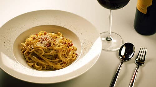 Teller Spaghetti in einer blassen Käse- und Eier-Soße mit schwarzem Pfeffer und Pökelfleisch.