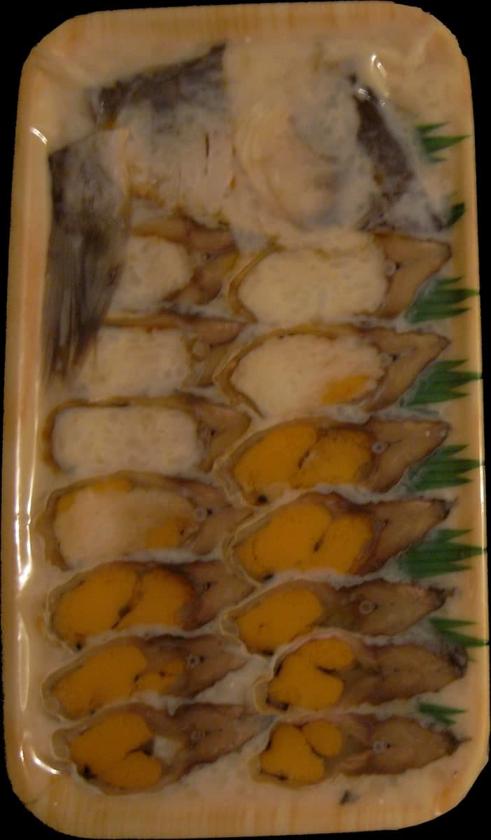 黄色・オレンジ色の保存米と薄く切った発酵魚の皿。