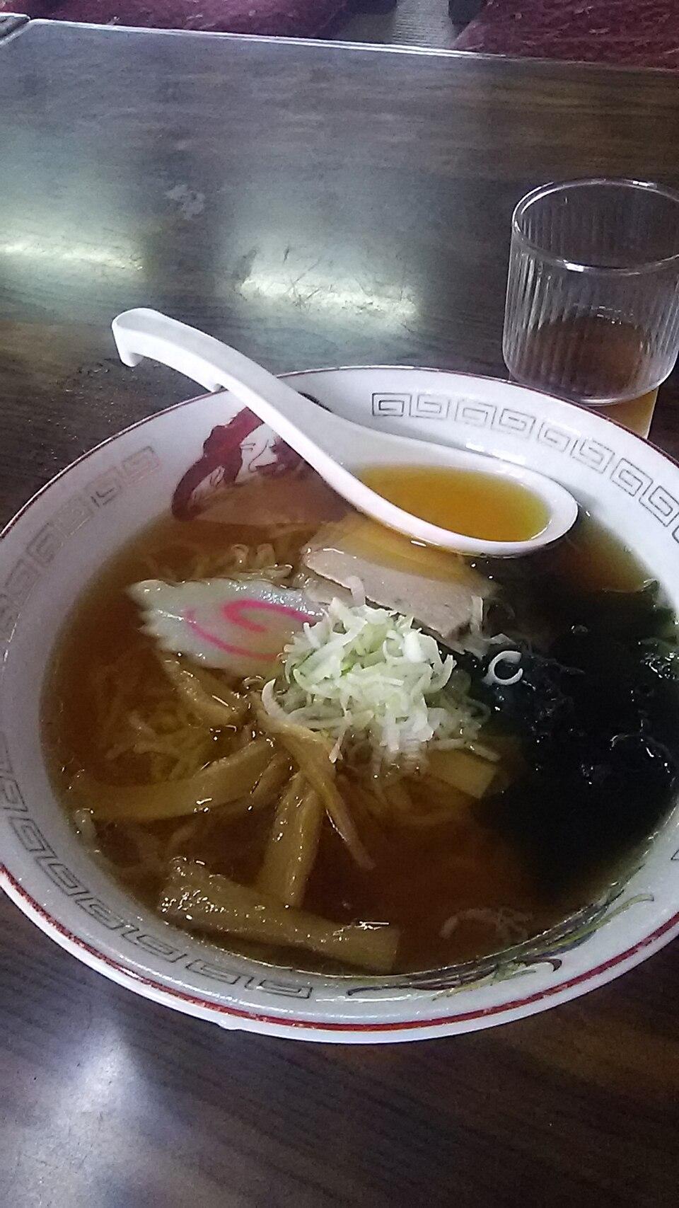 Eine Ramen-Schüssel mit leichter Brühe, flachen Nudeln, Schweinefleisch, Bambussprossen und Frühlingszwiebeln.