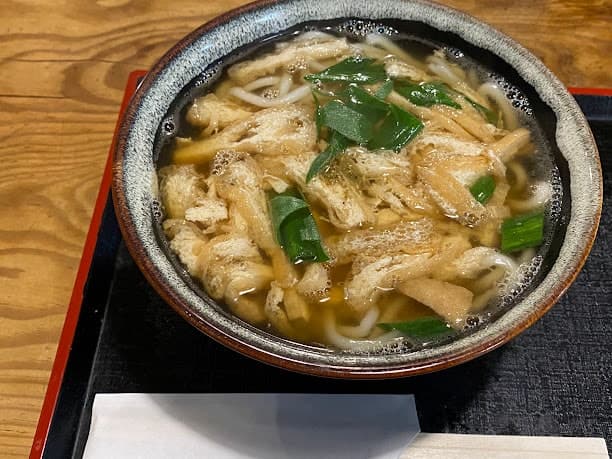 Schüssel mit Udon-Nudeln, garniert mit frittiertem Tofu in Brühe.