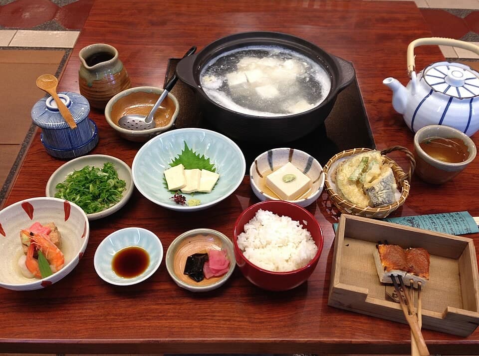 Tisch-Top Tofu-Hotpot mit kleinen Beilagen, Reis und Beilagenplatten.