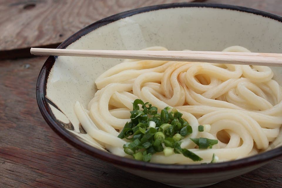 Nouilles udon épaisses servies simplement dans un bol avec oignon vert et bouillon à tremper.