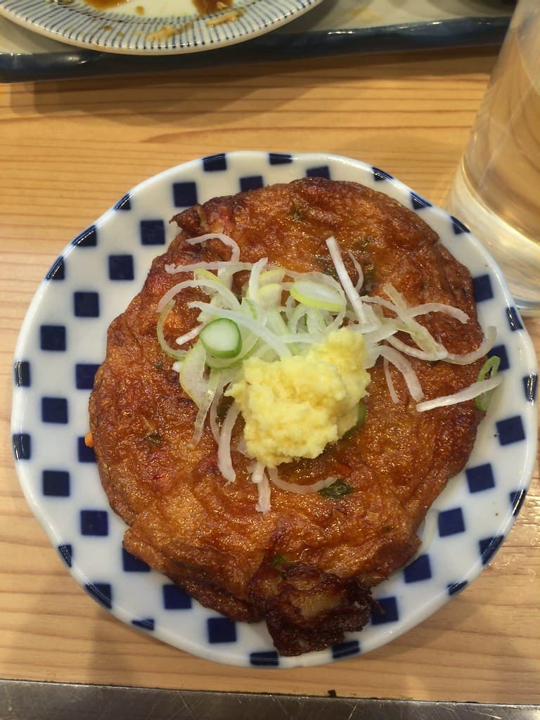 작은 무늬가 있는 접시에 담긴 둥근 튀김 생선 케이크와 생강, 파 슬라이스.