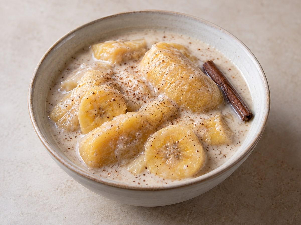 Morceaux de banane au lait de coco avec des épices chaudes dans un bol.