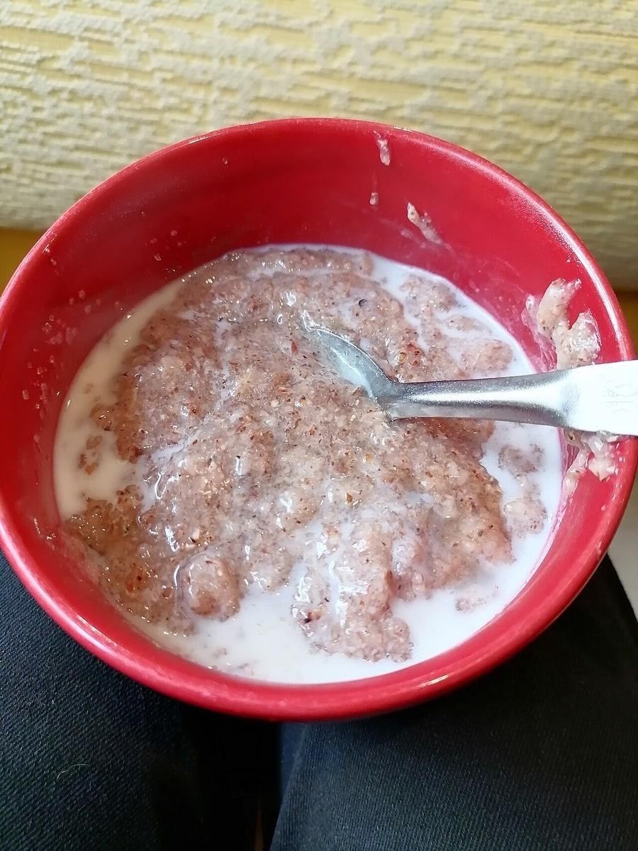 Rote Schale mit hellem fermentiertem Sorghumbrei und einem Löffel.