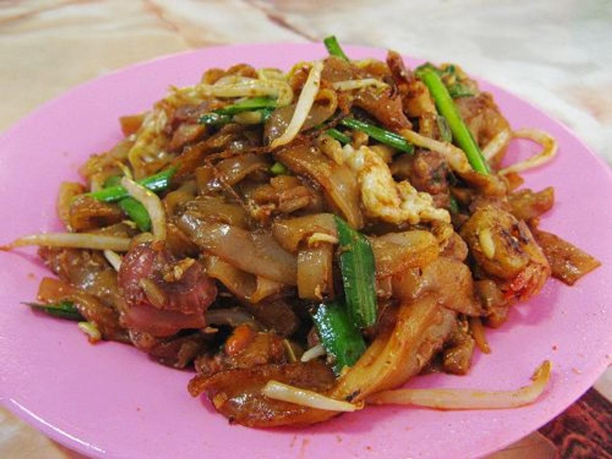 Teller mit wok-gebratenen flachen Reisnudeln mit Ei, Sprossen, Schnittlauch und Meeresfrüchten.