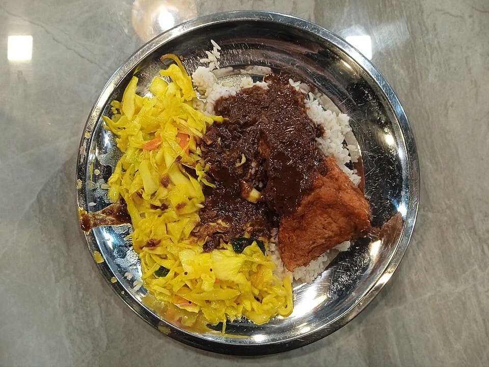 Teller mit Reis, mehreren Curry-Soßen, Gemüse und Beilagen.