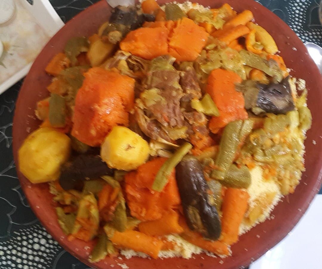 Große Platte mit Couscous, belegt mit Karotten, Kürbis, Zucchini, Rüben und anderem Gemüse.
