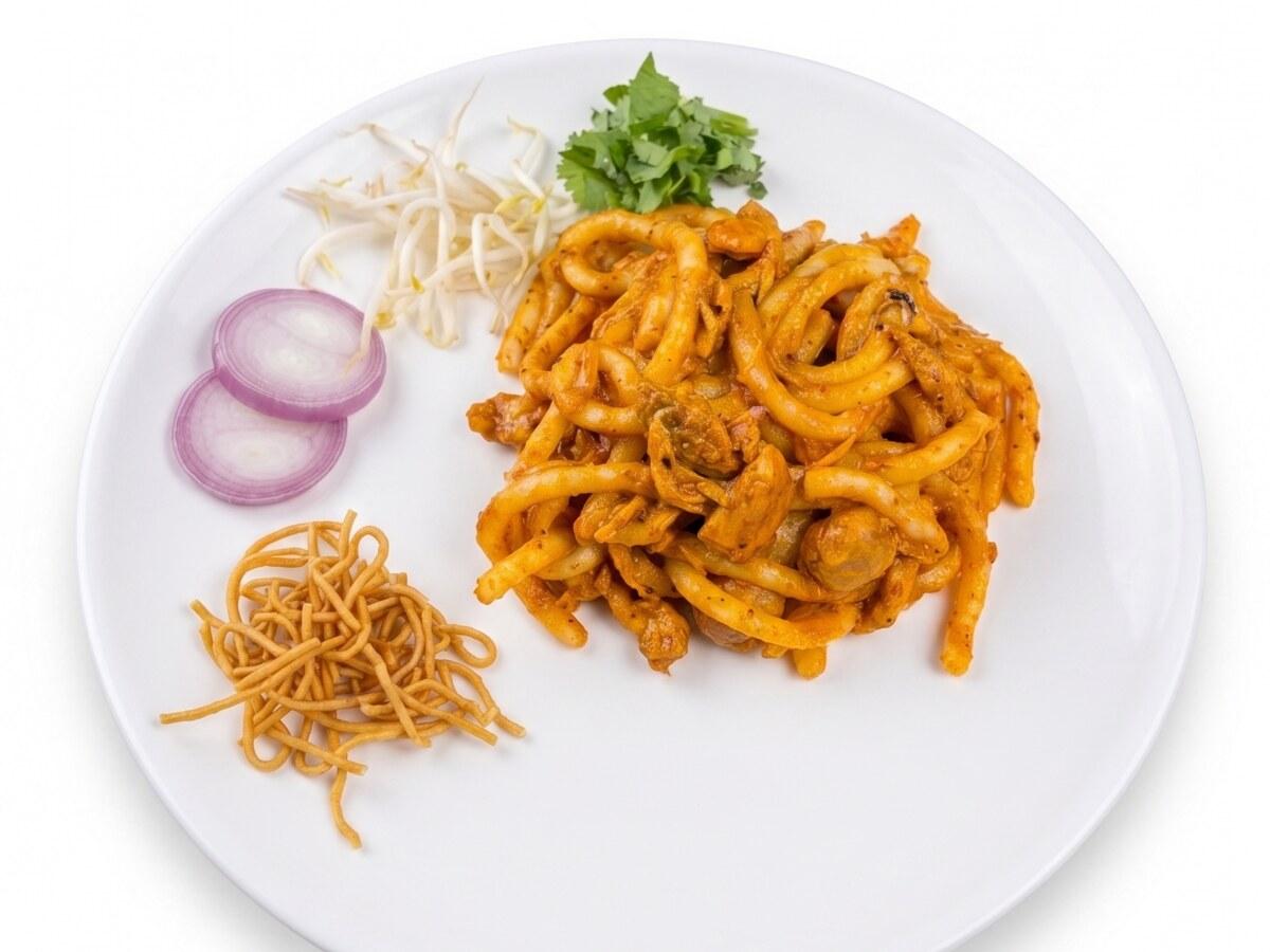 Piring mie tebal dengan kari, bawang, jeruk nipis, rempah, dan topping renyah.