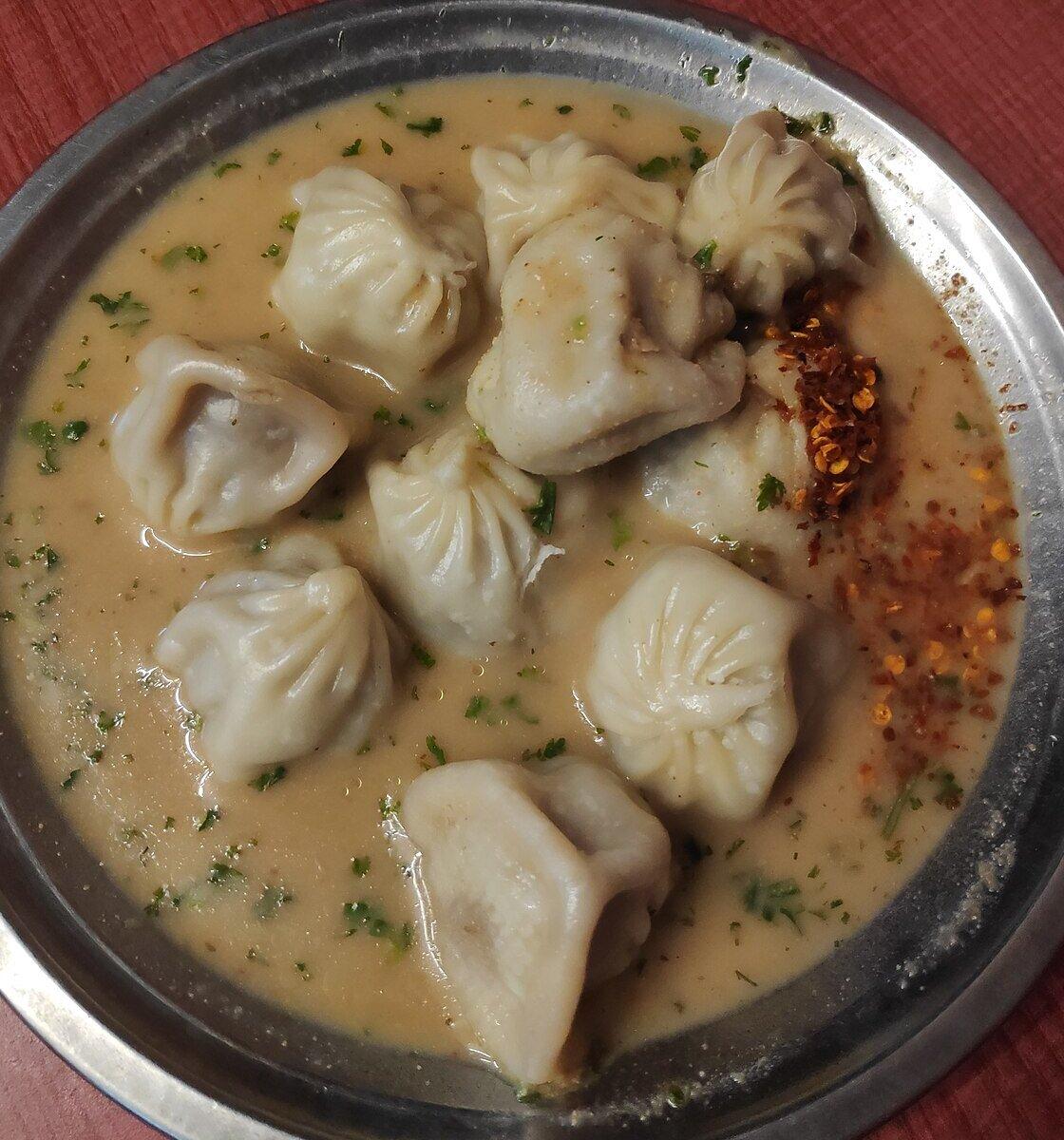토마토-참깨 칠리 소스가 담긴 그릇에 찐 만두.