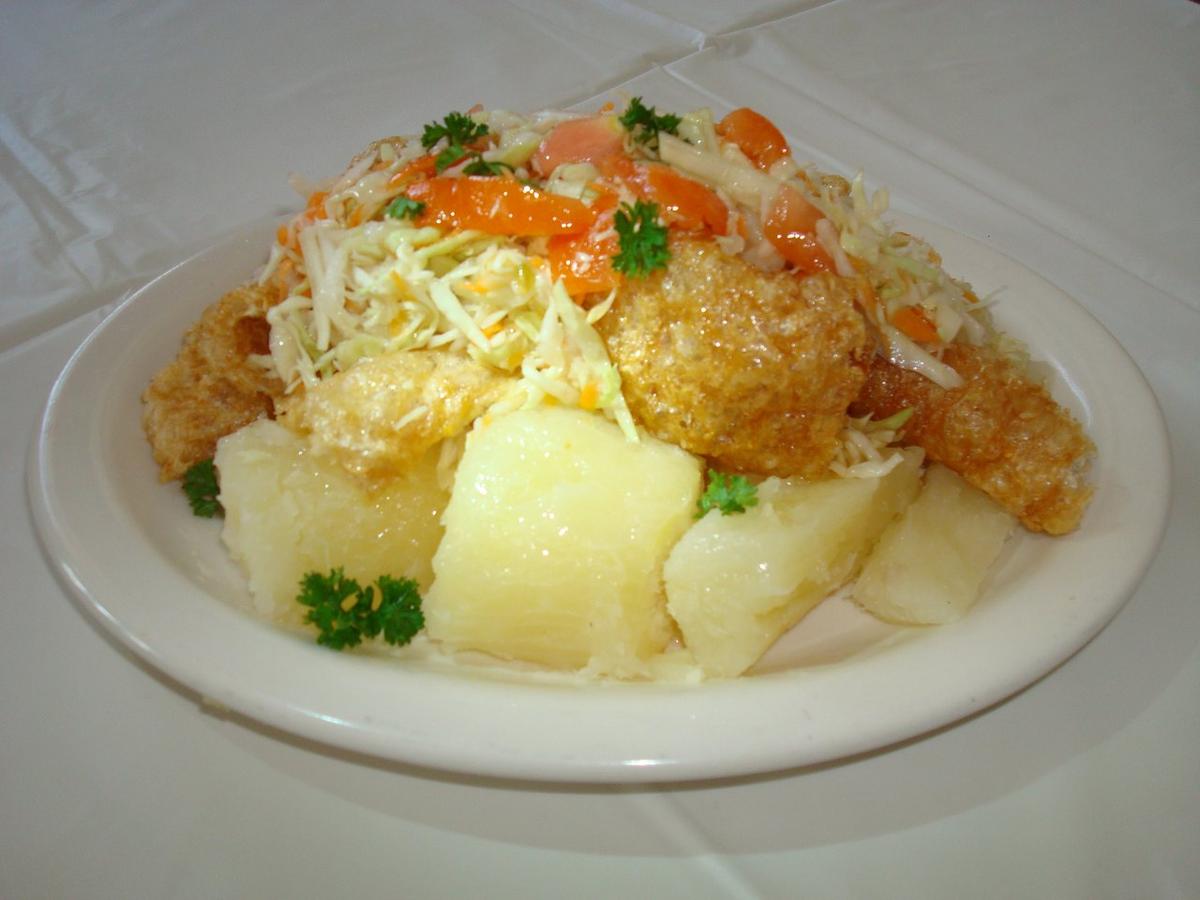 Gekochte Yuca, belegt mit Schweineschwarten, Krautsalat und Tomate.