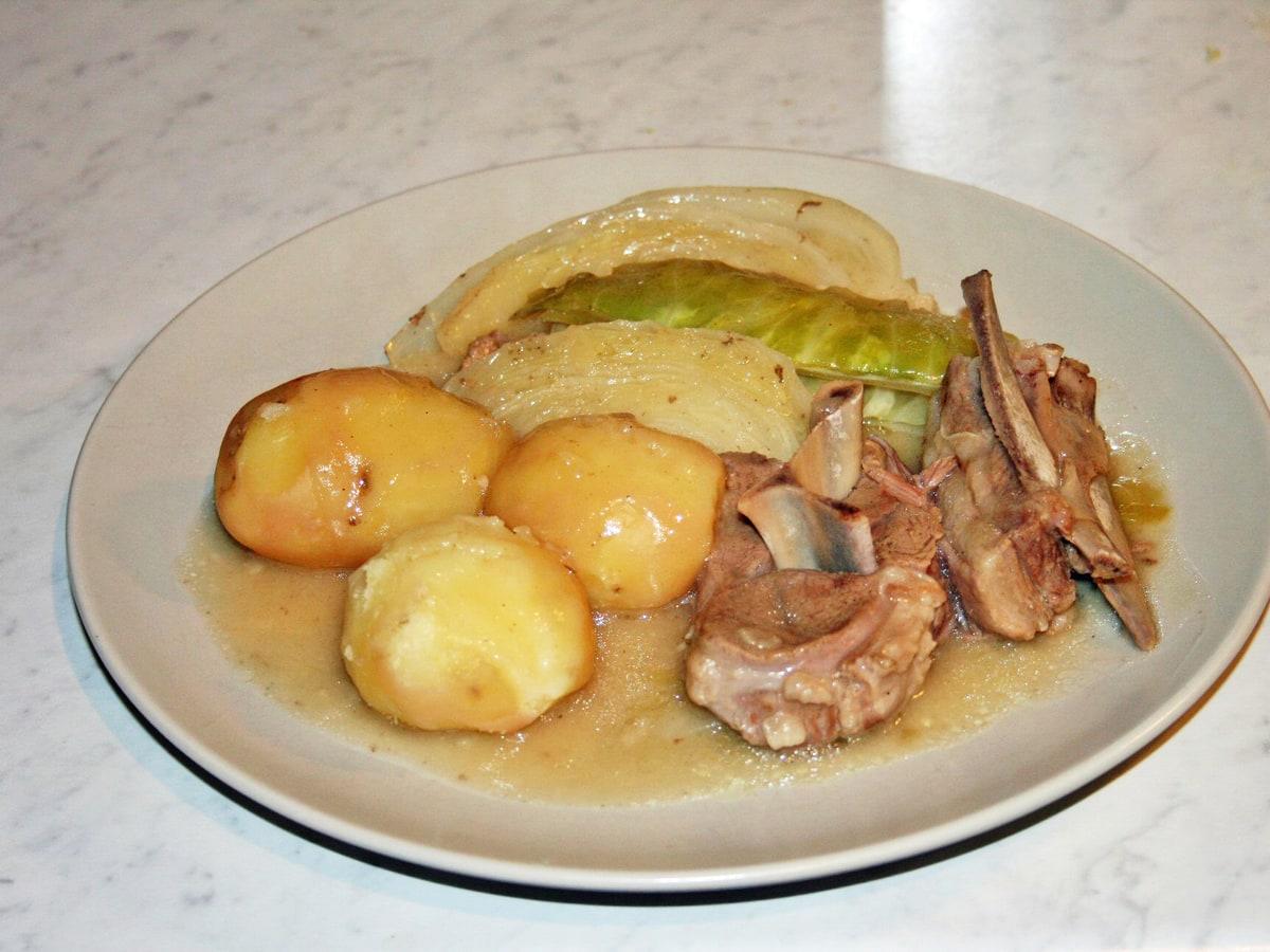 Teller mit Lamm-Kohl-Eintopf mit Kartoffeln in leichter Brühe.