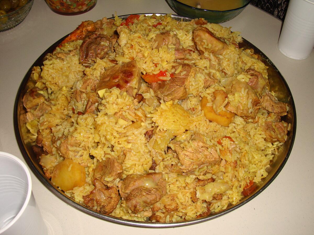 طبق كبير من الأرز المتبل الأصفر مع قطع اللحم والخضار بعد التقليب.