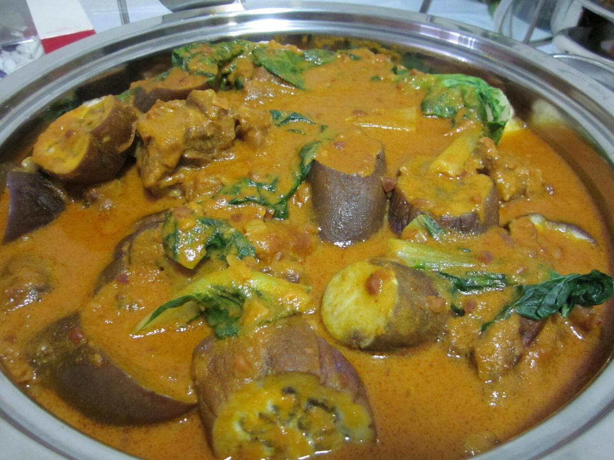 Oxtail and vegetables in a thick golden peanut sauce in a metal serving dish.