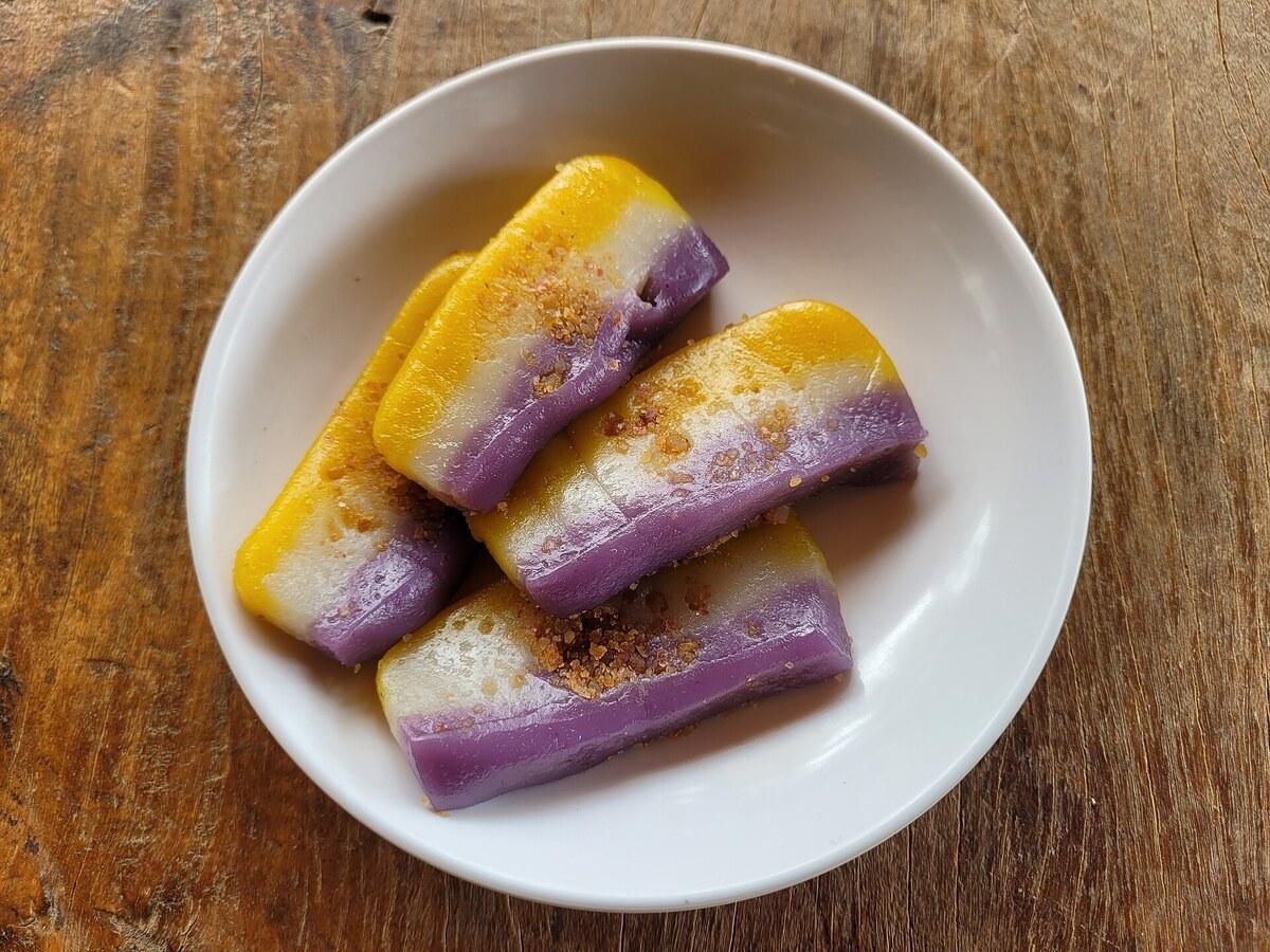 Rebanadas coloridas de postre de arroz pegajoso en capas sobre un plato sencillo.