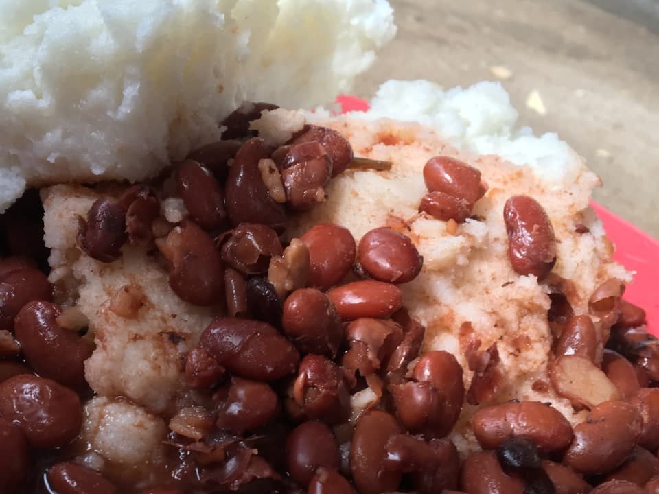 硬い白い粥の山に赤い豆がのった皿。