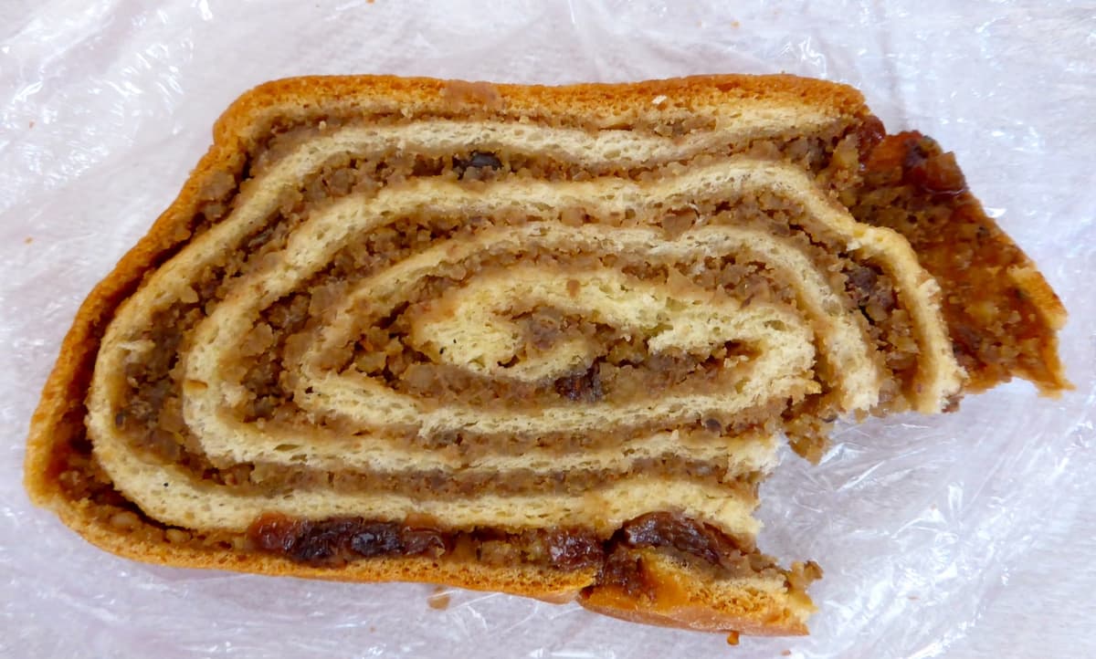 Rebanadas de pan dulce en espiral con relleno de nueces sobre una superficie de madera.