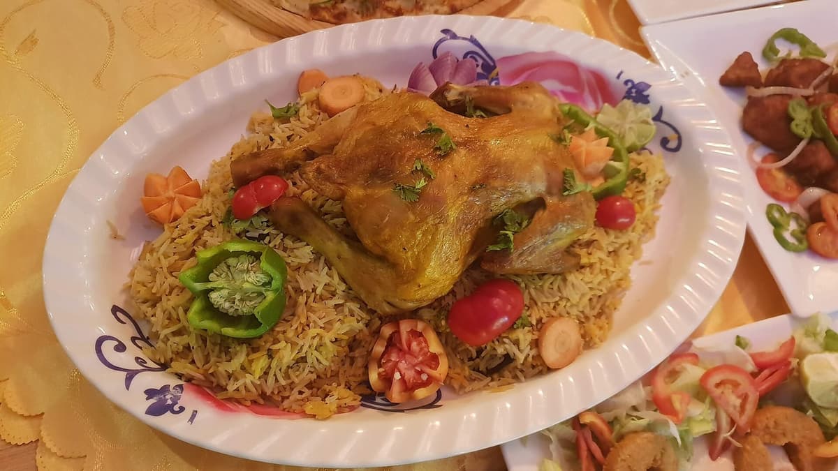 一盘香料米饭，上面放有熟鸡肉、蔬菜和小配料。
