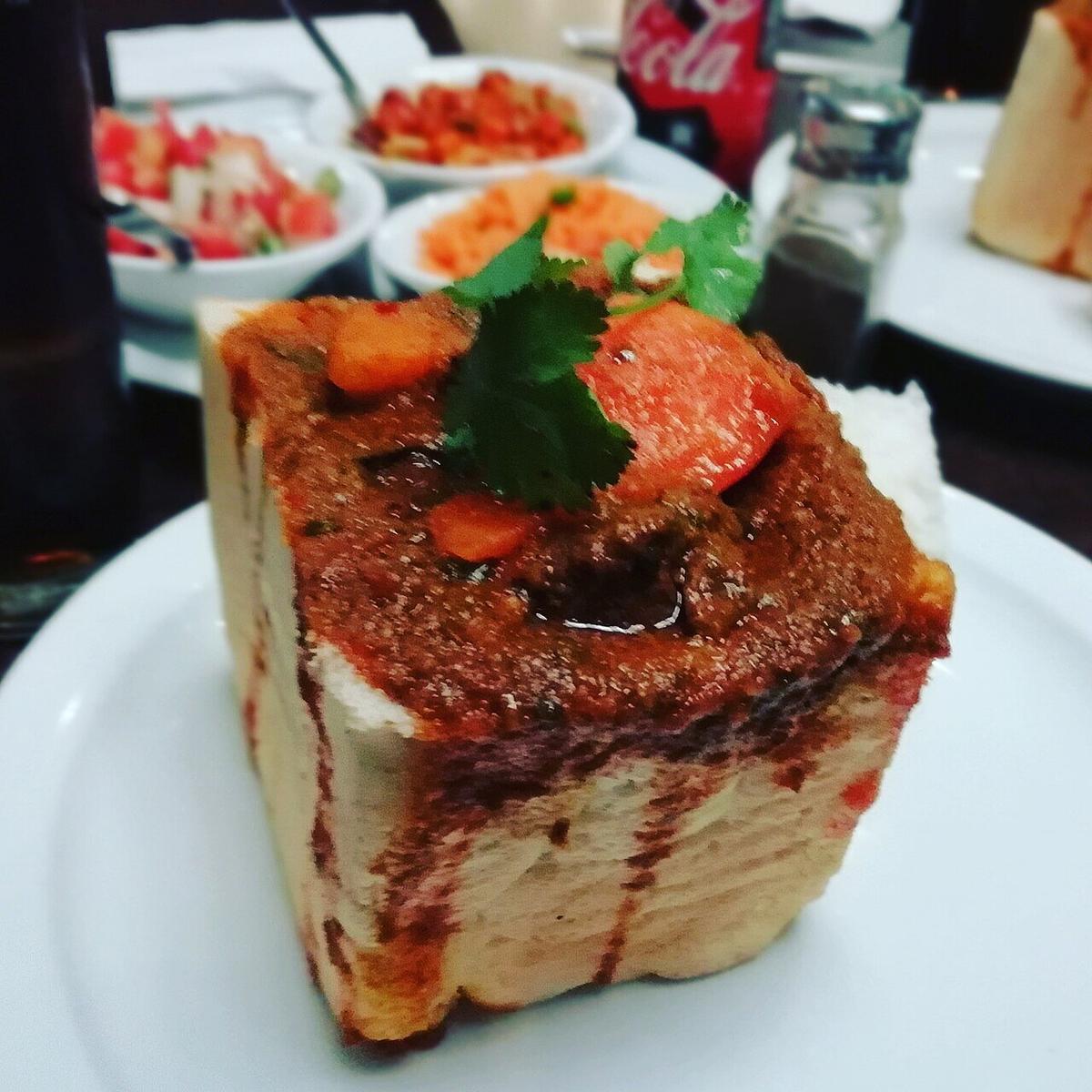 Pain évidé rempli de curry rouge-brun épais sur une assiette.