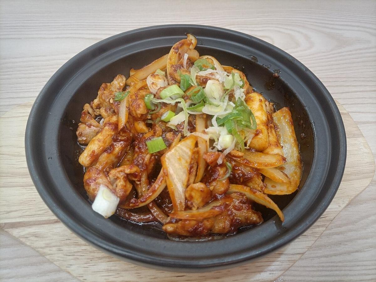 黒い皿に盛られた辛味の鶏肉と野菜の炒め物。