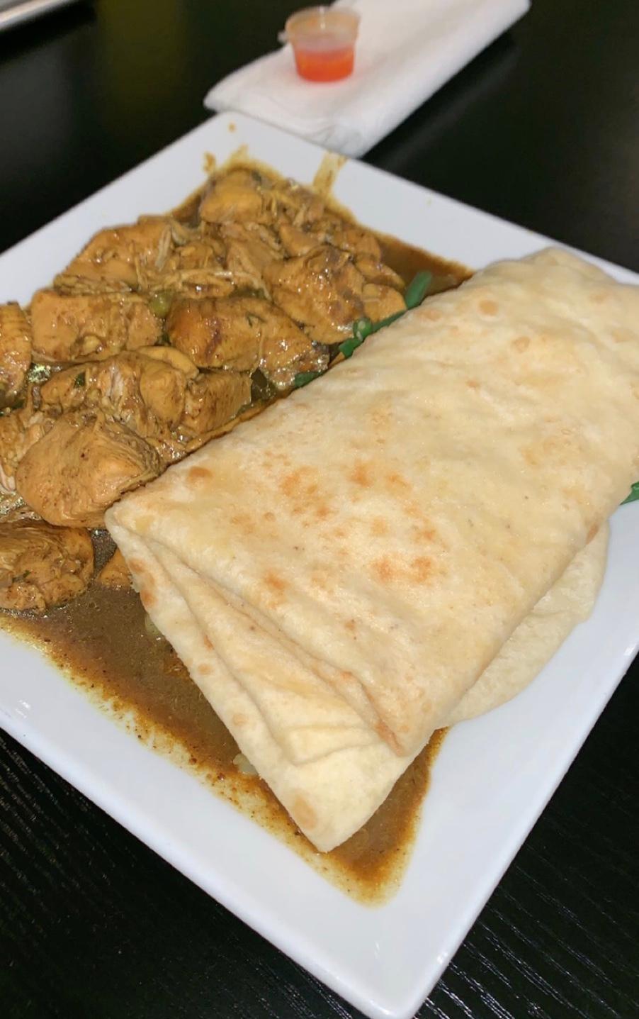 盘子上有 roti 薄饼、咖喱鸡肉和蔬菜。