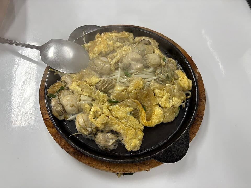 Omelet kerang renyah dengan telur dan kecambah dalam wajan panas.