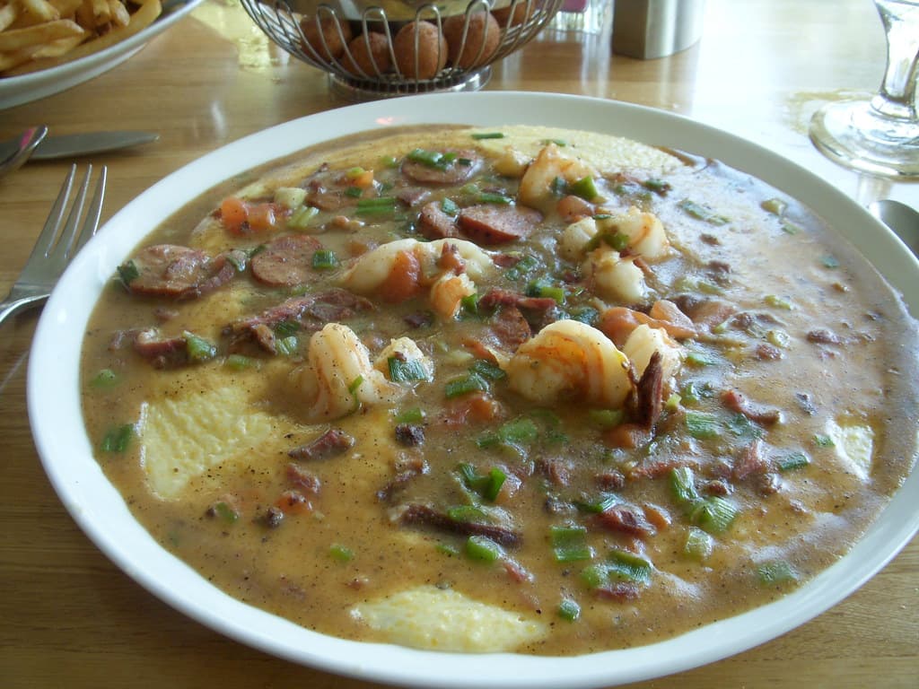 Garnelen und Grütze in einer flachen Schüssel mit Wurst und Frühlingszwiebeln.