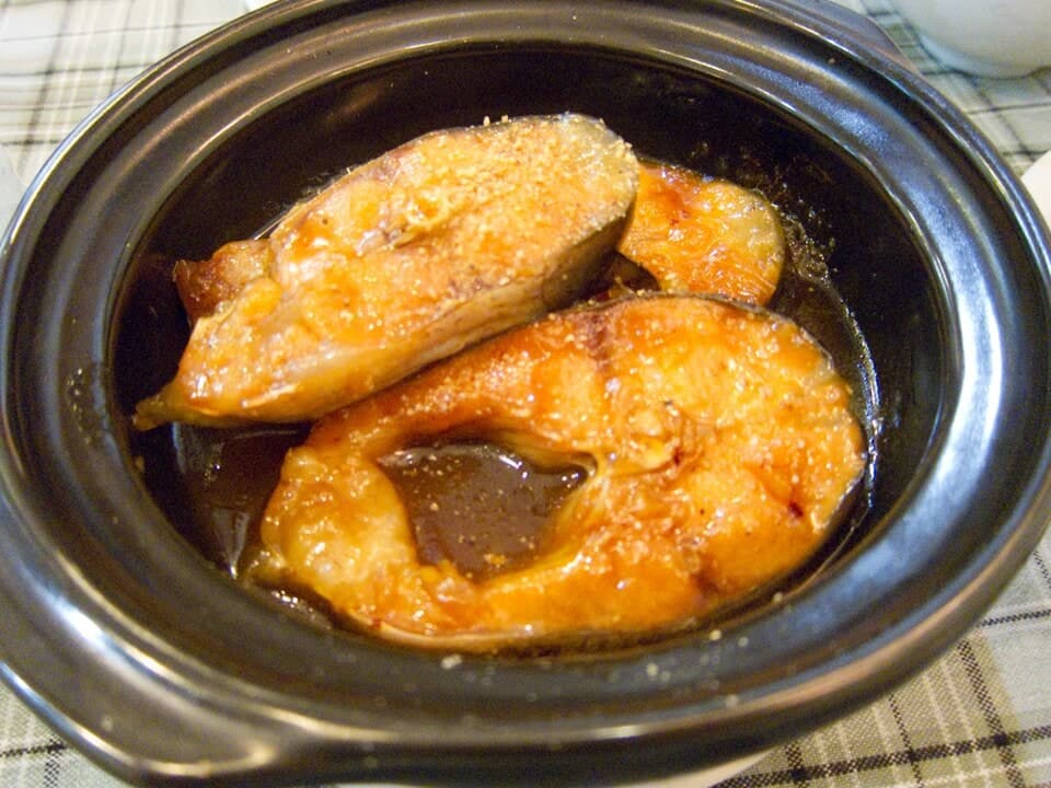 土鍋の中で濃く艶やかなソースで煮込まれた魚の切り身。