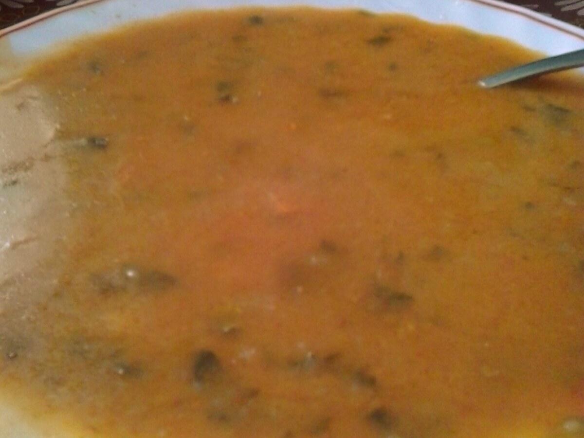 Nahaufnahme einer orange-braunen Suppe mit geröstetem Weizen in einer Schüssel.