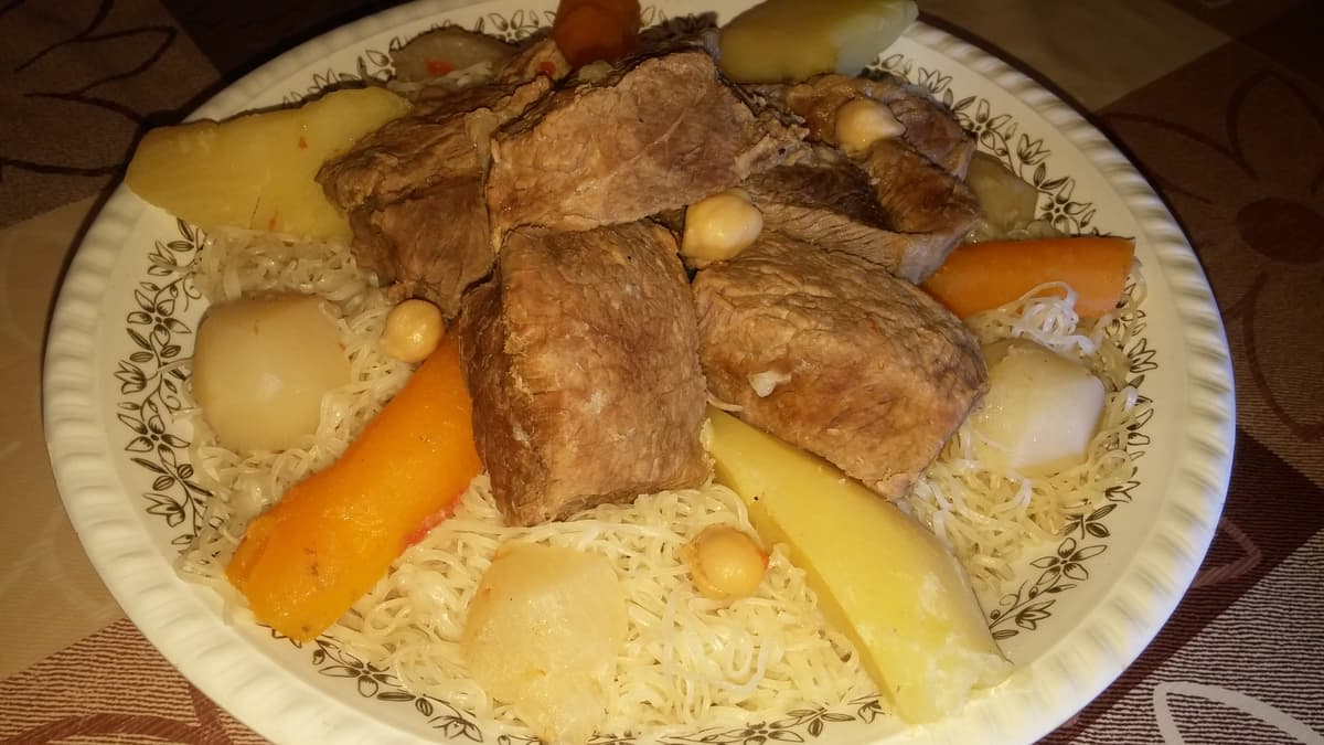 Dünne Nudeln, belegt mit Hähnchenstücken, Kichererbsen und Gemüse.