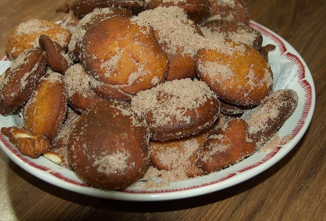 Piezas de masa frita azucaradas apiladas en un plato con patrón.