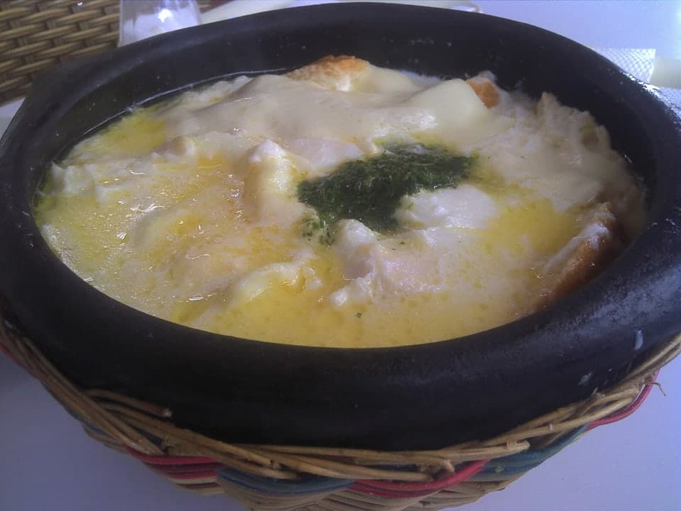 Dark bowl of milky soup with egg, herbs, and bread pieces.